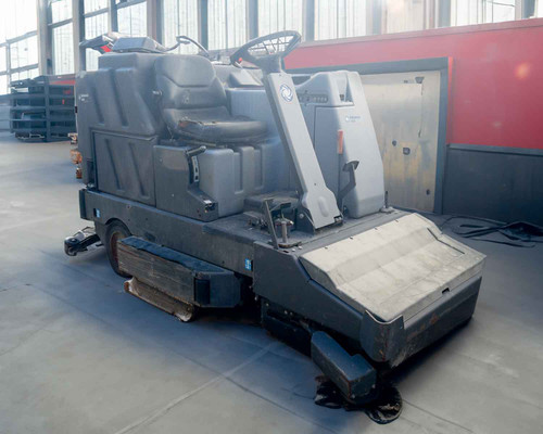 Nilfisk-Advance 3800 Rider Floor Scrubber Sweeper – right-front three-quarter view showing scrub deck, side brush, and operator seat