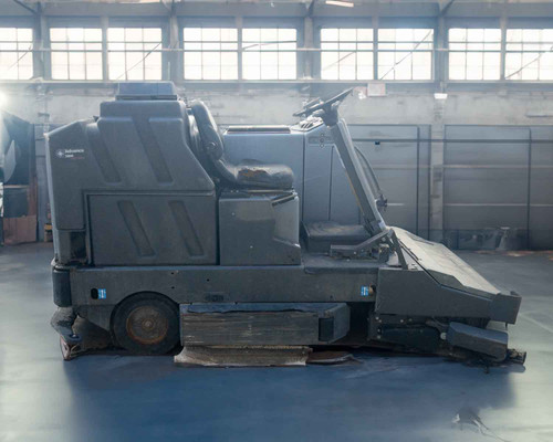 Nilfisk-Advance 3800 Rider Floor Scrubber – left-side profile view showing full machine length, worn brushes, and solution tank