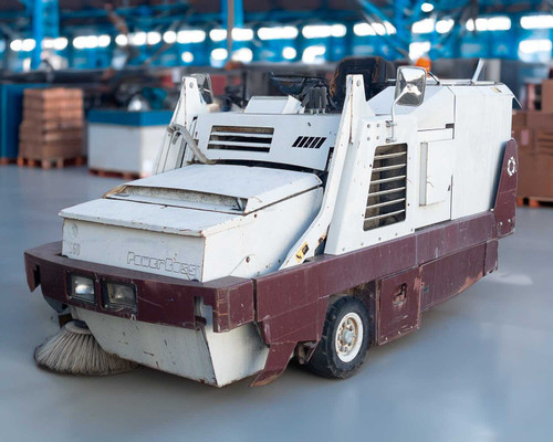 PowerBoss TSS/80-HD propane riding sweeper scrubber — front three-quarter view showing side brush, front bumper, and white and maroon body in warehouse