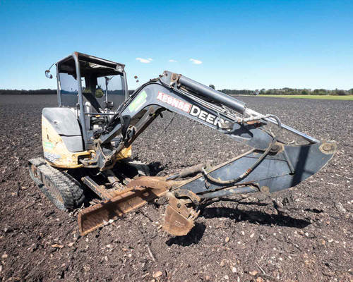 2013 John Deere 35G mini excavator in field — right side profile showing boom, arm, claw bucket, and dozer blade