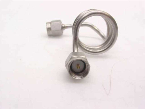 Close-up side view of coiled stainless steel SMA-male coaxial cable showing SMA-male connector with gold center pin