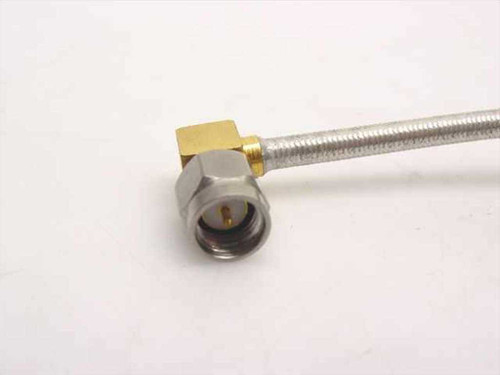 Close-up of right-angle SMA-male connector end of semi-rigid coax cable showing gold-plated body and center pin