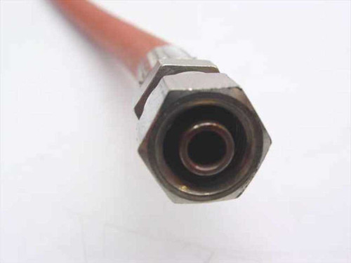 Close-up of hex compression fitting on one end of orange high pressure hose — face-on view showing bore