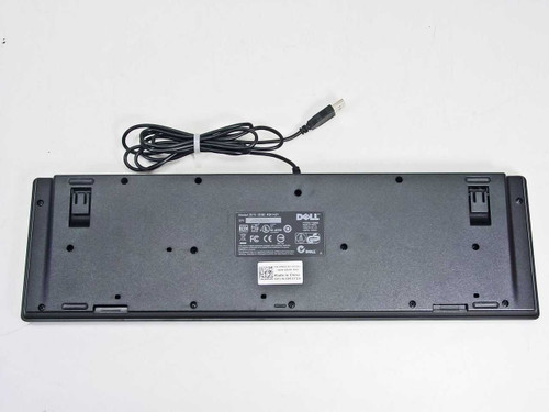 Dell KB1421 keyboard bottom view showing rating label, fold-out feet, and USB cable