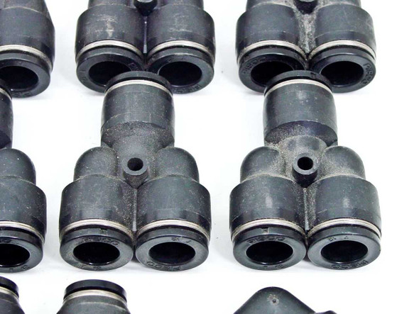 Close-up of black SMC Y-style and T-style push-to-connect pneumatic fittings showing collet ring detail and port openings