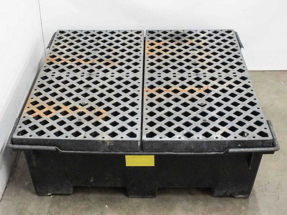 Spill containment sump pallet viewed from the front corner showing grating panels separated at center seam and sump basin walls