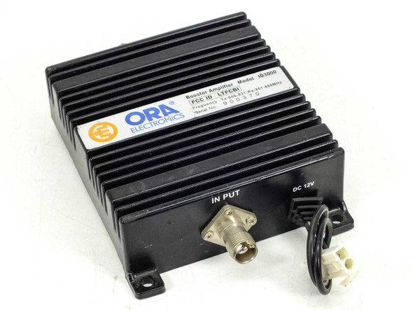 ORA Electronics ID3000 Booster Amplifier – front-left view showing BNC input connector and DC 12V power connector with heatsink enclosure