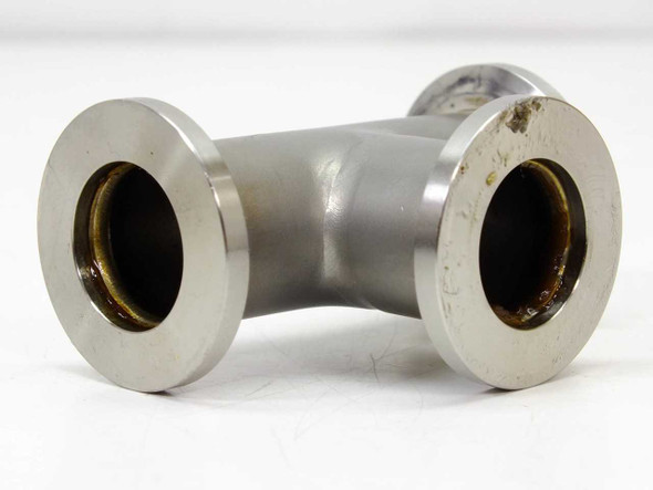Stainless steel KF25 NW25 tee fitting — straight-on front view showing all three flanged ports in T configuration; discoloration and light oxidation visible on flange faces
