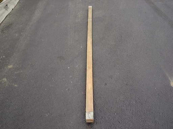 US Tucker Mfg Co military wood ridge tent pole, 9 feet long, laid flat on pavement — full length overhead view showing natural wood and metal end cap