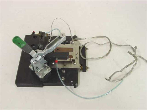 Custom PCB test jig fixture with Carr Lane toggle clamp, pneumatic tubing, PCB nest, and ribbon cables on black aluminum base plate — top angled view