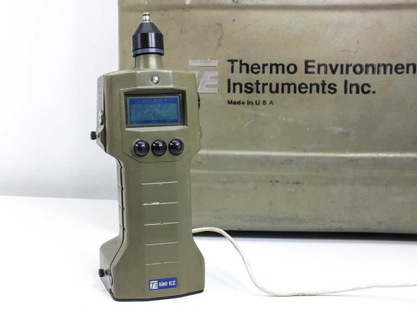 Thermo Environmental 580 EZ handheld VOC meter standing upright in front of its olive-drab hard carry case showing LCD display and front panel controls