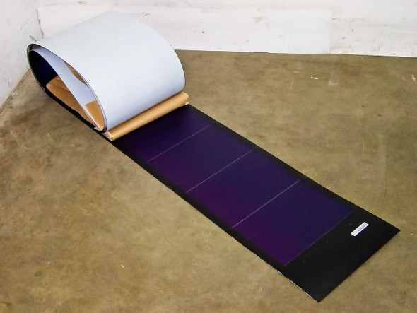 Uni-Solar PVL-128 128W flexible amorphous solar panel shown unrolled on floor, displaying dark purple photovoltaic cells and white backing
