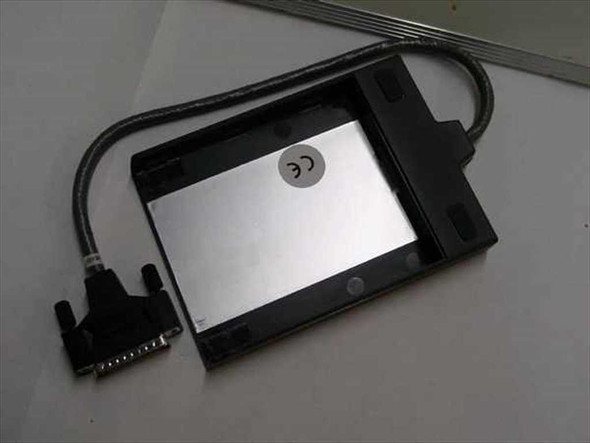 Compaq 258575-002 laptop floppy drive caddy bottom view showing CE mark and attached parallel cable