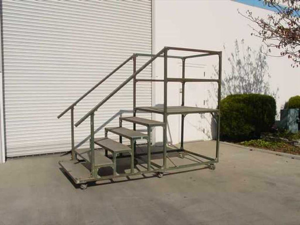 Mobile steel work platform with bolted steel frame, aluminum diamond plate steps, and perimeter safety rail — three-quarter front view outdoors