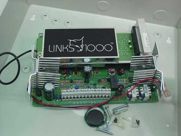 DSC Links 1000 alarm transmitter PCB close-up showing Links 1000 label, terminal strips, heat sink fins, capacitors, and included mounting screws and tamper button
