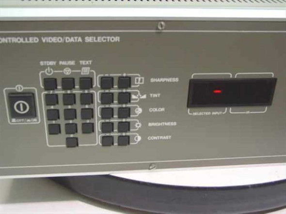 Barco RCVDS 800 front panel close-up showing power button, source selection keypad, Standby/Pause/Text controls, Sharpness/Tint/Color/Brightness/Contrast labels, and Selected Input LED display