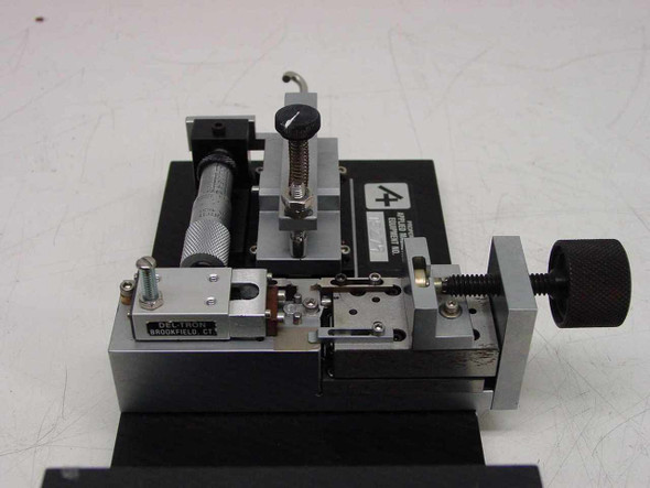 Applied Magnetics custom precision linear slide — top-front view showing micrometer adjustment barrel, spring-loaded clamp assembly, sliding carriage, and Applied Magnetics logo plate on black anodized base