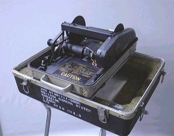 Dyna Metric KS-123A camera system open in transit case showing camera body, film transport mechanism, and Caution placard with federal stock label