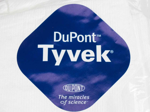 Close-up of DuPont Tyvek logo label on white coverall packaging — blue diamond logo reading DuPont Tyvek The miracles of science
