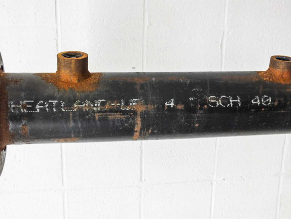 Close-up of Wheatland pipe body showing stamped markings reading WHEATLAND 4 SCH 40 with surface rust and black coating visible