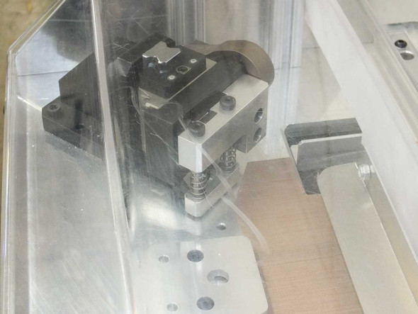 Close-up of left corner trimmer blade assembly – THK HSR20 linear guide carriage with slanted blade and spring-loaded mechanism