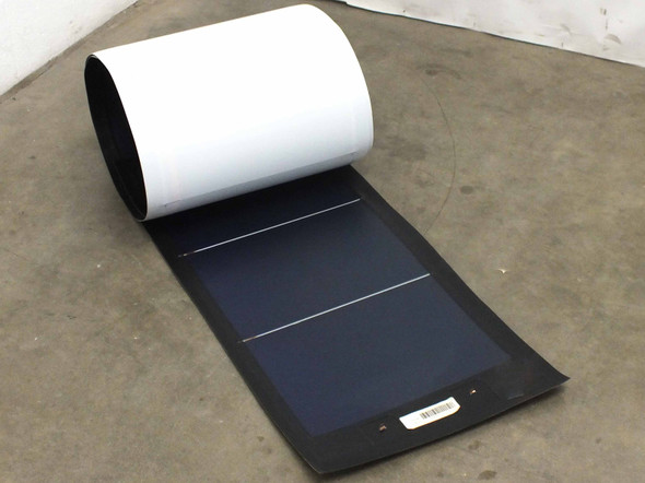 Xunlight XLS11-72 flexible solar panel partially rolled up showing black thin-film cell surface and white backing