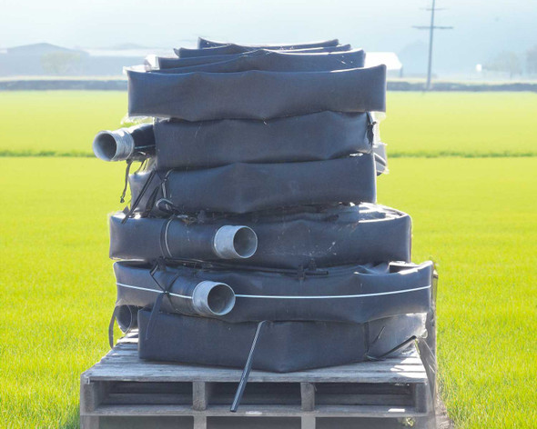 Toro Blueline 4-inch oval drip irrigation hose sections coiled and stacked on a wooden pallet in an agricultural field