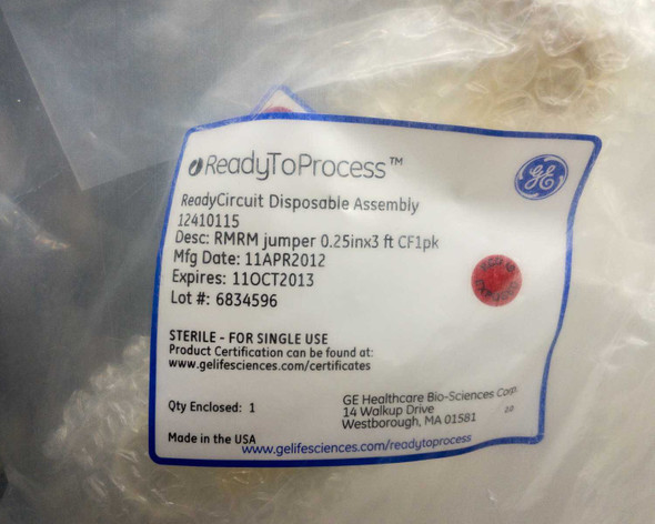 GE ReadyToProcess 12410115 label close-up showing RMRM jumper description, Mfg date 11APR2012, expiration 11OCT2013, lot number, sterile for single use, and Made in USA
