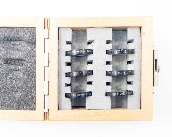 Six CVI Laser NIR bandpass filters in foam-lined wood case showing individual filter slots labeled F10-750 through F10-1000
