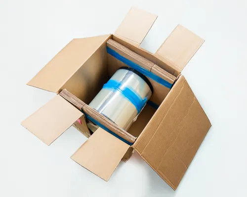 3M UBF 510-F ETFE solar film roll inside open cardboard shipping box with blue tape securing roll to cardboard backing