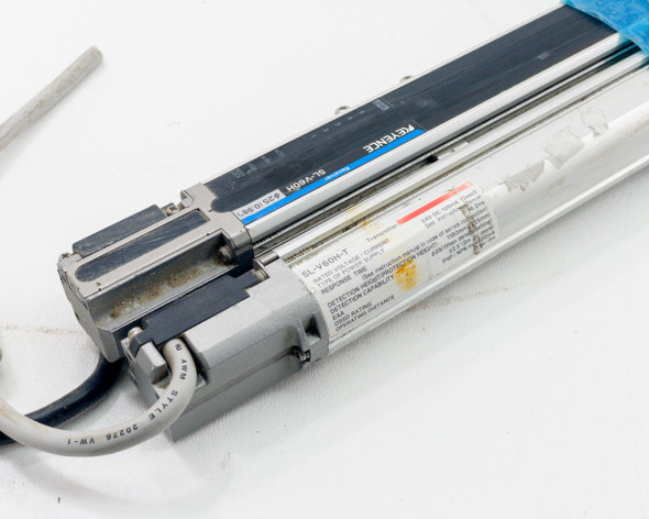 Close-up of Keyence SL-V60H-T transmitter and SL-V60H-R receiver end caps showing model labels, specification stickers, and cable connections