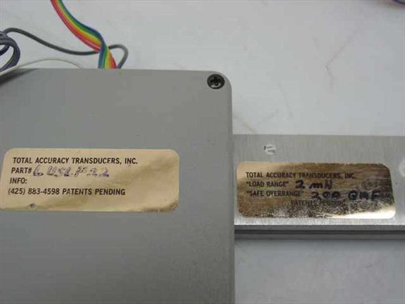 Close-up of Total Accuracy Transducers label on enclosure showing part number 6U48P52, and load cell beam label showing 2mN load range and 200 GMF safe overrange