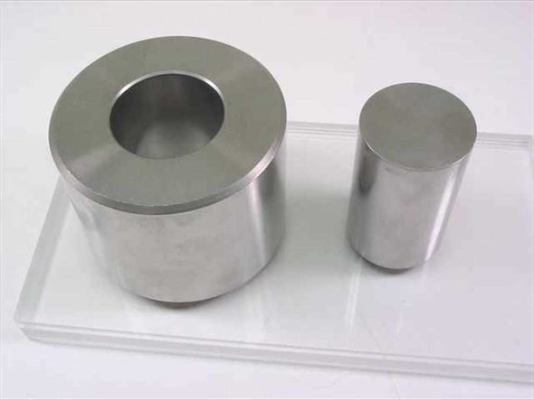 South Bay Technology die set — large hollow die body with matching cylindrical punch, shown side by side on clear acrylic tray
