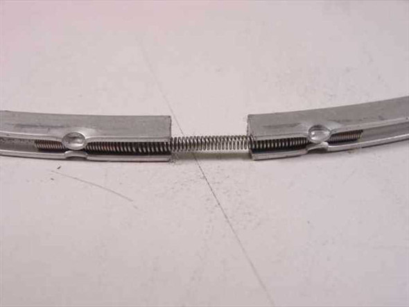 Close-up of spring-tension clamp joint on metal ring gasket showing spring mechanism and fastener detail