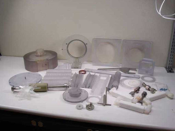 Full lot of plastic mixer spare parts spread on workbench — rotor bowl, impeller, blades, seals, fittings, and hardware