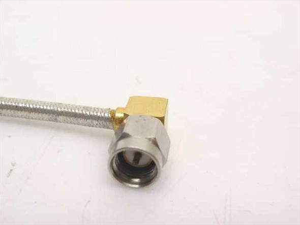 Close-up of right-angle SMA male connector end showing gold and stainless steel construction with 90-degree elbow body and hexagonal coupling nut