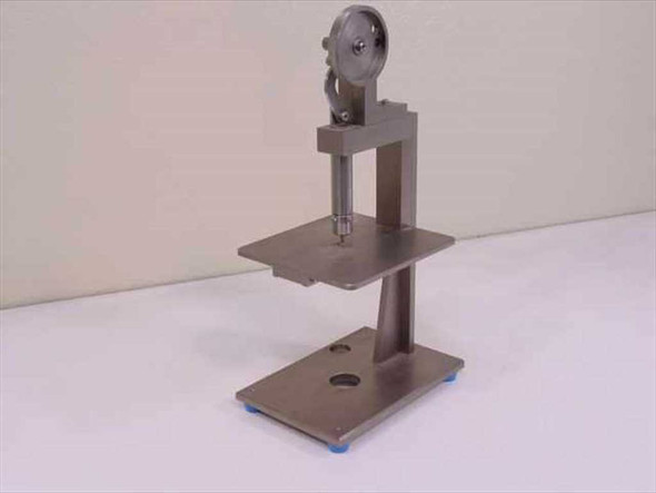 Custom tolerance measurement fixture front view showing vertical column, work table, base, and wheel actuator mechanism