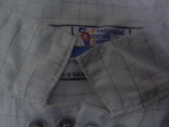 Prudential Overall Supply cleanroom frock interior label showing brand name and knit cuff detail with snap buttons