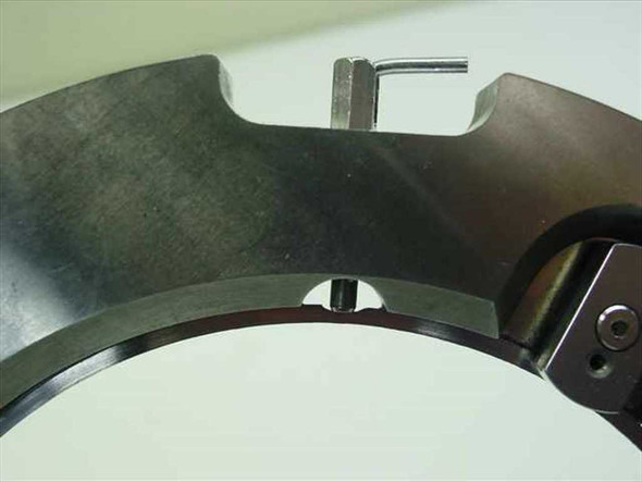 Close-up of tick mark flange side view showing spring-loaded alignment clip tab and inner edge detail