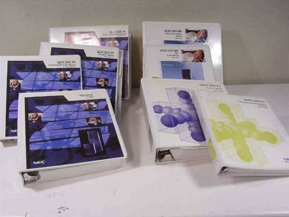 Full lot of nine NEC NEAX 2400 ICS IMX IPX PBX manual binders arranged on a table, showing all volumes