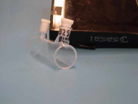 McCarthy Scientific Type 34 precision optical cell — close angled view showing cylindrical quartz cell body with white PTFE caps and handwritten marking '325' on glass
