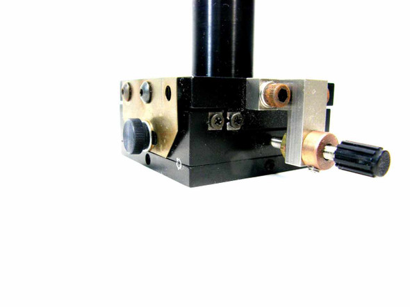 Close-up of linear stage base showing drag screw knob, brass collar, stainless adjustment screw, and mounting hardware detail