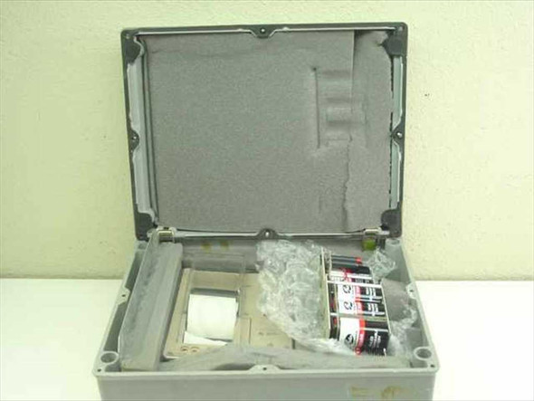 Large gray weatherproof enclosure open showing foam-lined lid, CR21 Micrologger inside, battery packs, and documentation