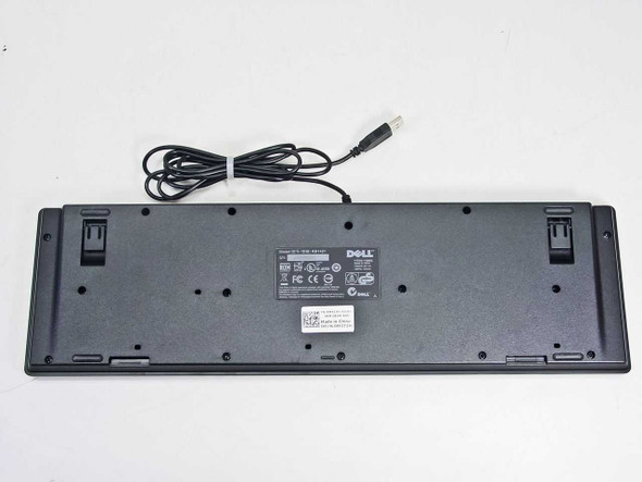 Dell KB1421 keyboard bottom view showing rating label, fold-out feet, and USB cable