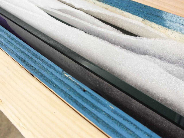 Yamashita Denso PXS-0855MP — close-up of crate packing materials showing stacked foam sheets, optical glass panel, and textile layers used to protect flash tester components