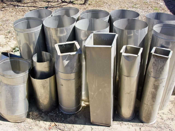 Mixed lot of 13 stainless steel ventilation duct sections grouped outdoors — round cylinders and square sections visible