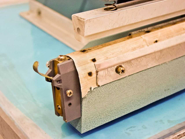 AIE AIE-605A1 close-up of left end of sealing bar showing heating element, PTFE tape, and end clamp hardware