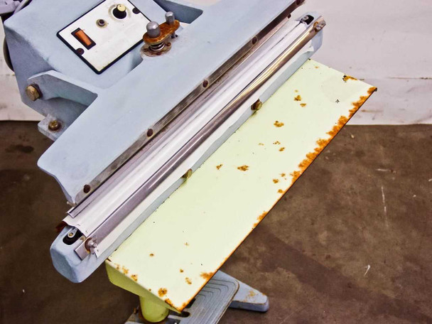 TEW TISF-452 top-down view of sealing table showing rust spots and corrosion across the yellow painted surface