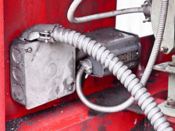 Interior electrical junction box and conduit connections inside red-painted cabinet