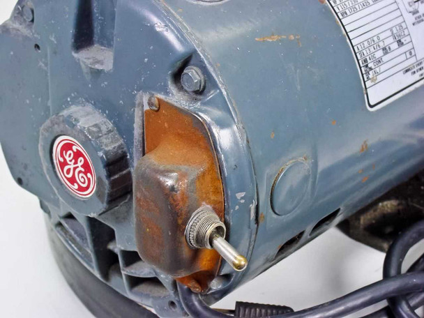 GE motor end cap close-up – showing GE logo, capacitor cover with visible surface rust, and motor shaft terminal